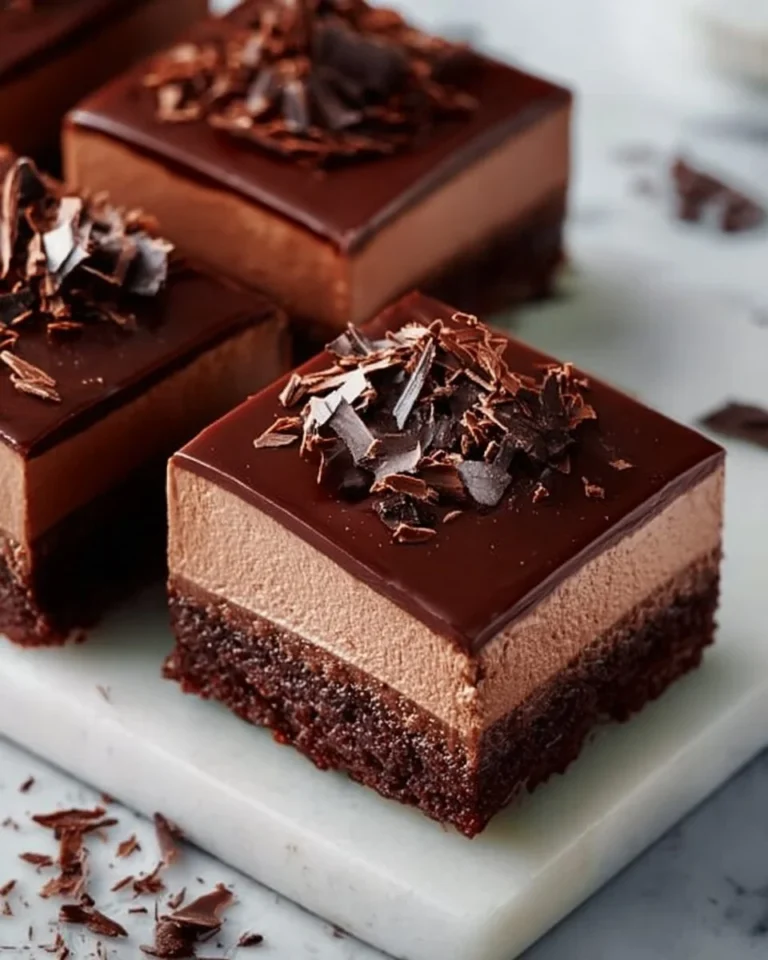 Decadent Chocolate Mousse Brownies stacked on a plate with a chocolate drizzle