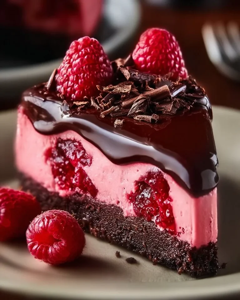 Decadent dark chocolate raspberry cheesecake with fresh raspberries and chocolate garnish.