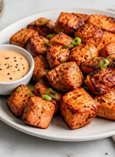 Creamy air fryer salmon bites with Bang Bang sauce on a plate