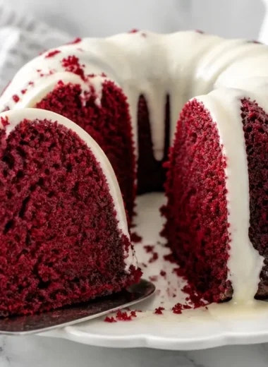 Red Velvet Bundt Cake drizzled with Cream Cheese Glaze on a white plate